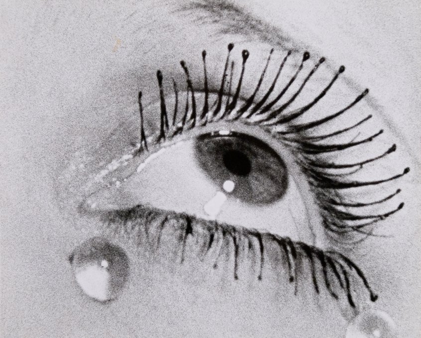 Man Ray, Larmes, um 1930, Gelatinesilberpapier, Print 24,1 x 29,9 cm, Schenkung Gruber 1984, Museum Ludwig, Köln Repro: Historisches Archiv mit Rheinischem Bildarchiv/ Sabrina Walz & Jana Dorn © Man Ray 2015 Trust / VG Bild-Kunst, 2026 Schwarz-Weiß-Nahaufnahme eines geöffneten Auges mit auffällig langen, fächerförmig angeordneten Wimpern. Auf Irisund Pupille sowie auf der Haut unterhalb des Auges sind helle Lichtreflexe zu sehen. Die Aufnahme betont die Strukturder Wimpern, die Lidkonturen und die feinen Hautdetails.