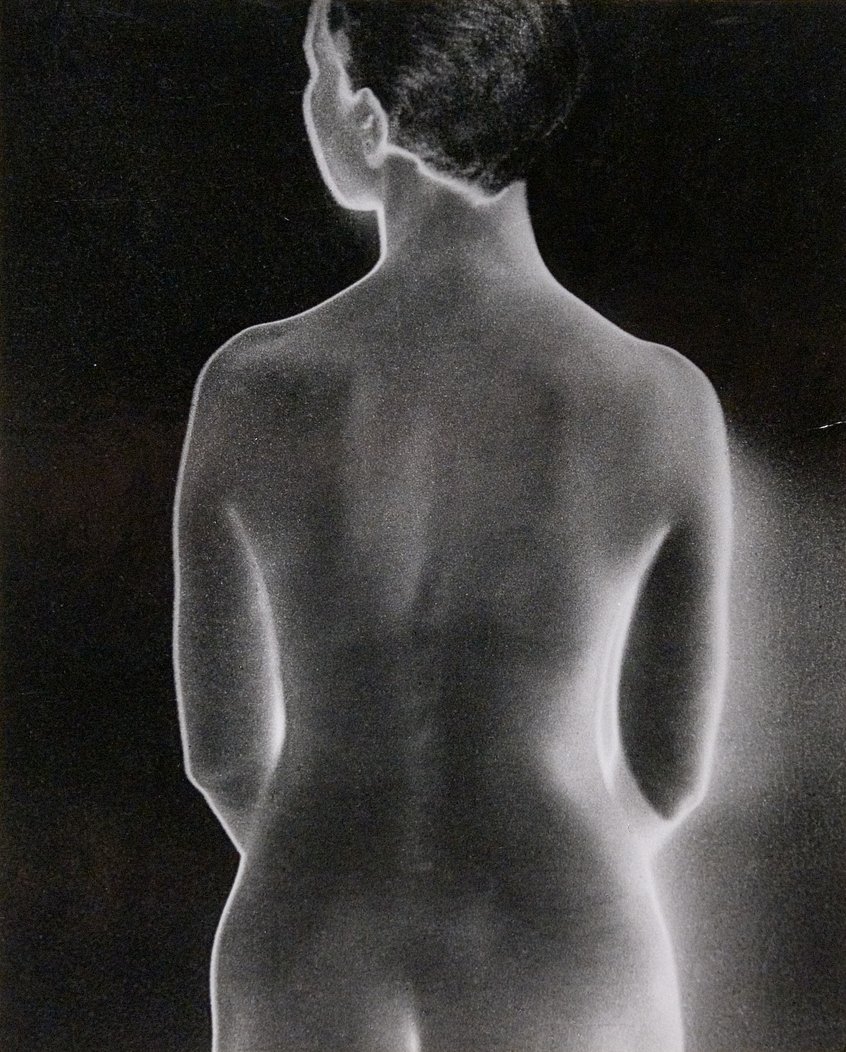 Man Ray, Ohne Titel (Solarisierter Rückenakt), 1929, Gelatinesilberpapier auf Karton, solarisiert 25 x 20 cm Schenkung Gruber 1993, Museum Ludwig, Köln Repro: Historisches Archiv mit Rheinischem Bildarchiv/ Sabrina Walz & Jana Dorn 1. Schwarz-Weiß-Aufnahme des Rückens einer unbekleideten Person in Rückenansicht. Der Kopf ist leicht zur Seite gedreht, die Arme liegen seitlich am Körper. Die Aufnahme hebt die Konturen von Schultern, Wirbelsäule, Taille und Hüften durch starke Hell-Dunkel-Kontraste hervor.